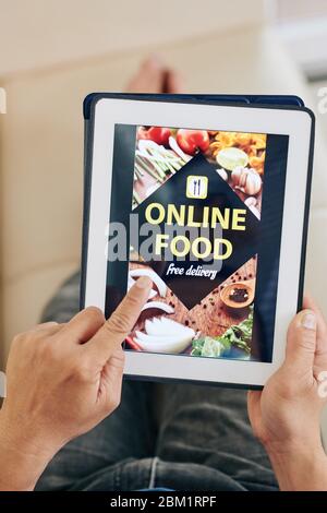 Man using supermarket application on tablet computer to order contact free food delivery during pandemic Stock Photo