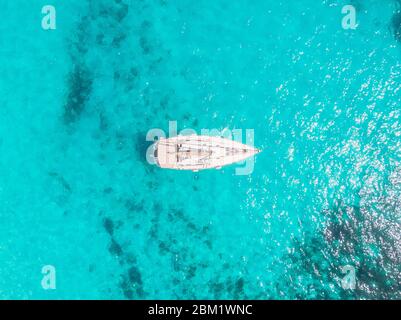 Aerial top view white yacht with sail stands on coral reef in blue transparent turquoise sea. Concept travel Stock Photo