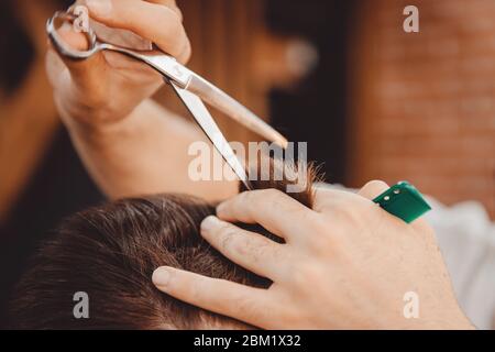 Close-up of man haircut, master does the hair styling in barber shop Stock Photo