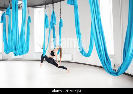 Young beautiful women practicing aerial yoga stretching in gym Stock Photo