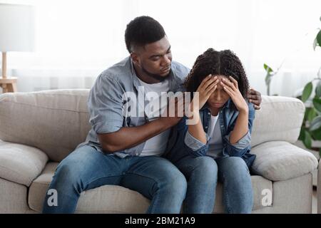 Supportive black man comforting his upset girlfriend at home, expressing empathy