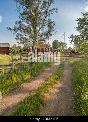 Small country road and old traditional red cottages in a rural landscape at the village Stensjo by. Oskarshamn, Smaland, Sweden, Scandinavia Stock Photo