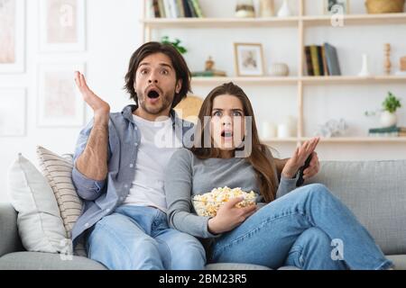 Couple watching horror and eating popcorn, home interior Stock Photo