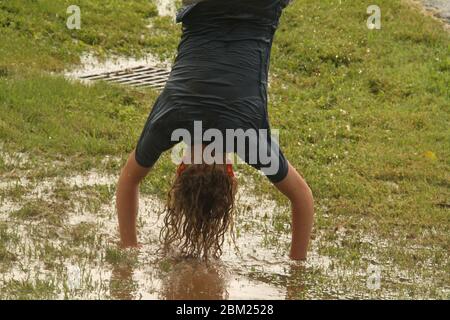 Young girl having fun getting wet in puddles formed after heavy rain Stock Photo