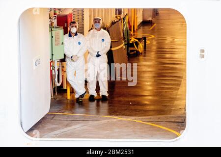 Crew members wearing protective suits as a precaution against the spread of corona virus, after the ship docked.Cruise ship Regal Princess has docked in Rotterdam with about nine hundred Europeans, at least ten are Dutch. The ship returns crew members from other cruise ships to Europe. As far as it is known, no one is infected with the corona virus. Stock Photo