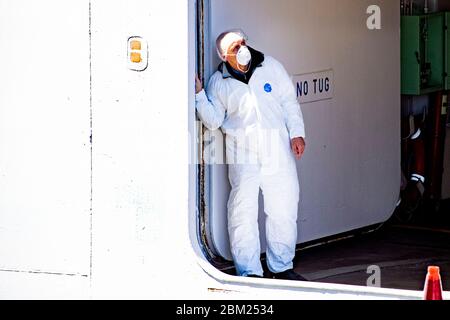 A crew member wearing a protective suit as a precaution against the spread of corona virus, after the ship docked.Cruise ship Regal Princess has docked in Rotterdam with about nine hundred Europeans, at least ten are Dutch. The ship returns crew members from other cruise ships to Europe. As far as it is known, no one is infected with the corona virus. Stock Photo