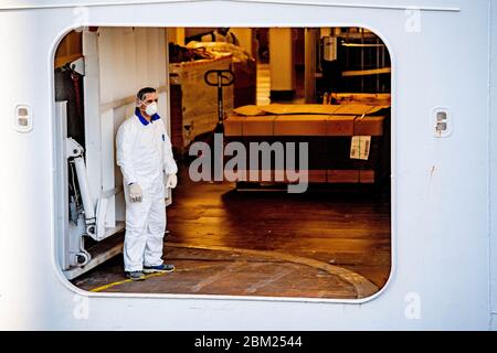 A crew member wearing a protective suit as a precaution against the spread of corona virus, after the ship docked.Cruise ship Regal Princess has docked in Rotterdam with about nine hundred Europeans, at least ten are Dutch. The ship returns crew members from other cruise ships to Europe. As far as it is known, no one is infected with the corona virus. Stock Photo