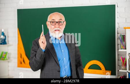 spend hours studying, back to school. protractor ruler. learn geometry easily. become good at math. stem in classroom. senior man teacher use tool at blackboard. bearded tutor in glasses. Stock Photo