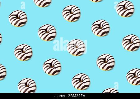 Pattern made of glazed donut on blue background. Party food concept with copy space. Top view. Stock Photo