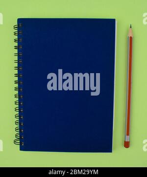 Silver and red striped wood pencil crayon placed beside a blue color paper diary Stock Photo