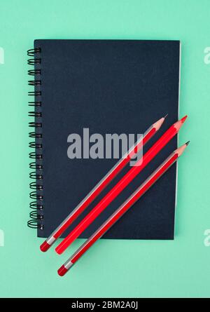 Some red colored wood pencil crayons placed on top of a blue color paper diary Stock Photo