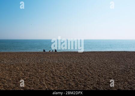A young family sitting on the shingle beach at Deal, Kent, UK Stock Photo