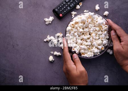Man hand holding a bowl of popcorn on gray background  Stock Photo