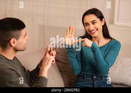 Couple Sitting On Sofa Communicating With Sign Language Stock Photo
