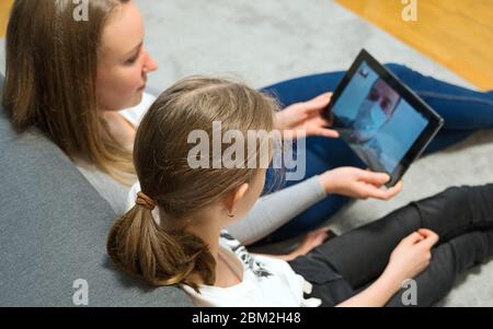 Woman and her daughter communicate with dad, who is in quarantine. Stock Photo