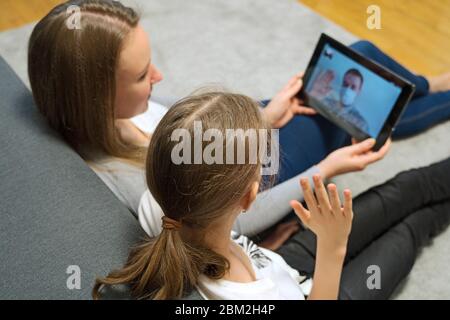 Woman and her daughter communicate with dad, who is in quarantine. Stock Photo