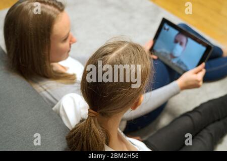 Woman and her daughter communicate with dad, who is in quarantine. Stock Photo