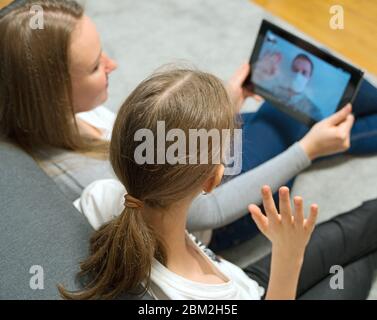 Woman and her daughter communicate with dad, who is in quarantine. Stock Photo
