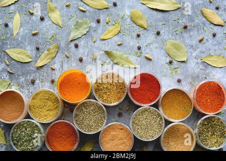 Variety of colorful dried herbs and spices in cups. Selection of herbs and spices on grey background. Cooking, eating concept. Top view. Stock Photo