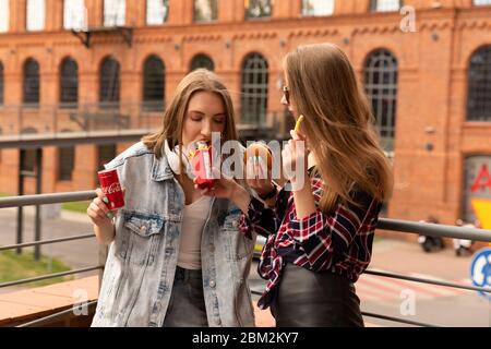 LODZ, POLAND - AUGUST 17, 2019: two young girls eat food from a chain of McDonald's restaurants and drink Coca-Cola. Stock Photo