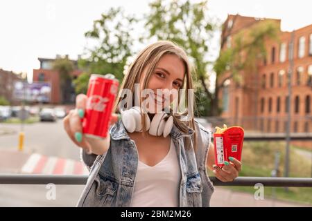 LODZ, POLAND - AUGUST 17, 2019: a young girl eats french fries from a McDonald's restaurant chain and drinks Coca-Cola. Stock Photo