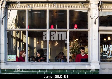 London, UK - November 03, 2019: View through the window of people inside Market Cafe pub on Broadway Market, a shopping street in the heart of Hackney Stock Photo