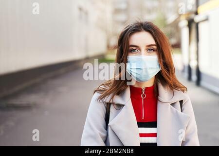 Young woman with beautiful blue eyes and disheveled hair wearing protection face mask against coronavirus MERS-Cov, Novel coronavirus 2019-nCoV Stock Photo