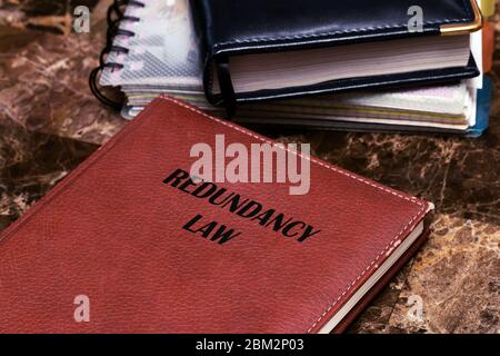 Redundancy law about termination and employee right. The text is written on a book lying on a marble table. Stock Photo