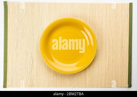 Yellow plate on a bamboo napkin, top view Stock Photo