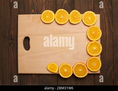 Fresh orange sliced fruits on a wooden table and cutting board. Natural and healthy food. Arranged as a frame with blank space in center. Stock Photo