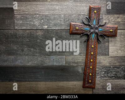 Beautiful decorative christian cross with Texan inspired motifs with spurs and cowboy belts. Concept of religion and beliefs in the USA Stock Photo