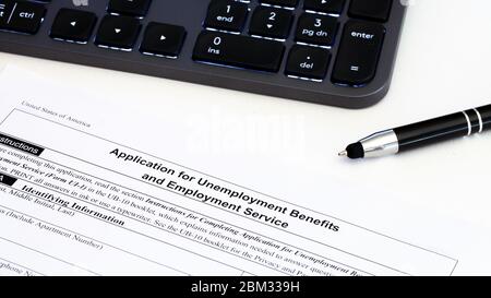 Application for employment benefits form with computer keyboard and pen on white background. Unemployment concept Stock Photo