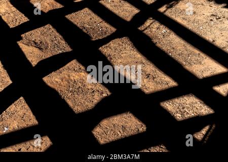 Fence shadow on the corral sand floor, Diamantina, Minas Gerais, Brazil Stock Photo