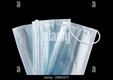 Face masks, blue disposable medical sanitary surgical masks closeup, isolated on black background Stock Photo