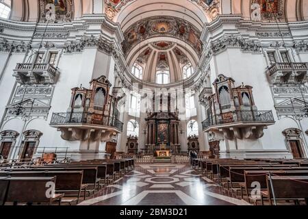 Feb 4, 2020 - Salzburg, Austria: Upward angle of central dome ceiling mural paintings and organ pipe over pews in the nave of Salzburg Cathedral Stock Photo