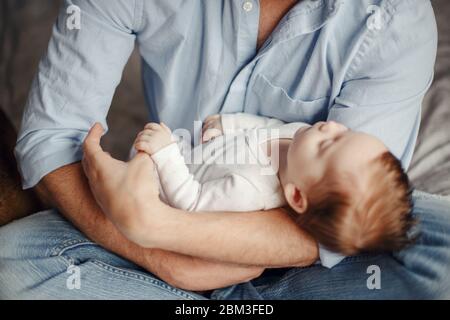 Newborn baby holding father parent finger while sleeping. Parent holding rocking child daughter son in hands. Authentic lifestyle parenting fatherhood Stock Photo