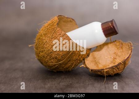 Bottle sticks out in a coconut shell on gray background. Fresh organic coconut milk. Delicious substitution for lactose intolerant or vegan Stock Photo