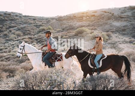 Young people riding horses doing excursion at sunset - Wild couple having fun in equestrian tour  - Training, culture, passion, healthy lifestyle, spo Stock Photo