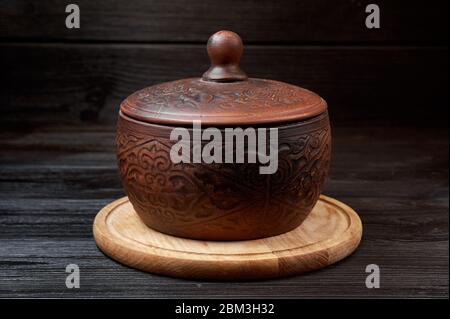 brown clay pan on a black wooden background with authentic carvings Stock Photo