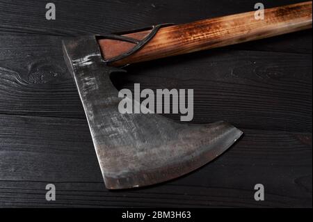real scandinavian ax on a black wooden background, still life, viking ax, burnished steel Stock Photo