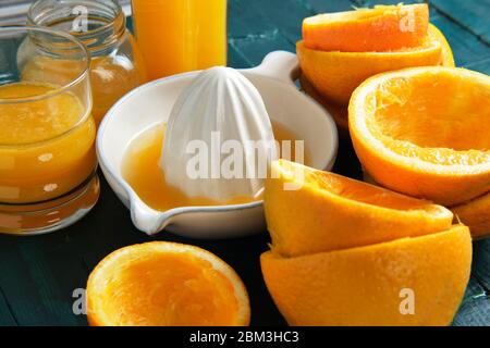 White ceramic juicer with orange peels and orange juice on a green woo Stock Photo