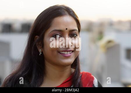 Face portrait of an Indian brunette woman smiling on rooftop Stock Photo