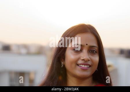 Face Portrait of an Indian brunette woman smiling on rooftop Stock Photo