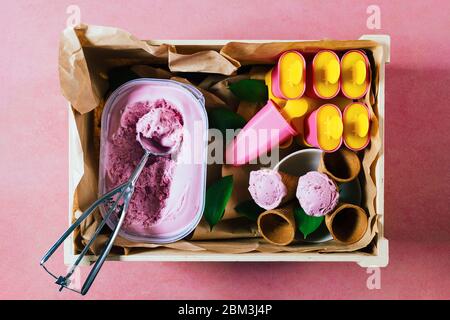 Delicious strawberry ice cream and refreshing popsicles in a rustic wooden box. Ice cream ready to eat on a summery day outdoors. Stock Photo