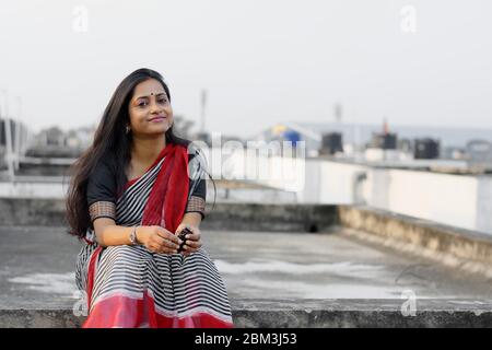 Portrait of a smiling Indian brunette woman son rooftop at sunset time Stock Photo