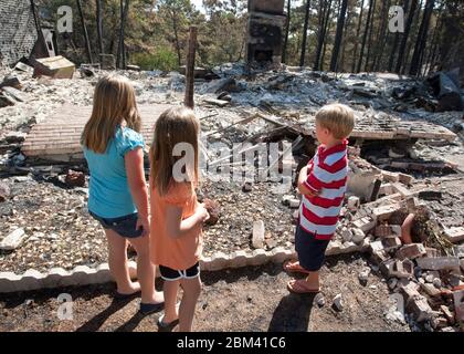 Bastrop County Texas USA, September 9, 2011: Somber children look at the remains of a home destroyed during massive wildfires that swept through their wooded neighborhood earlier in the month.  ©Marjorie Kamys Cotera/Daemmrich Photography Stock Photo