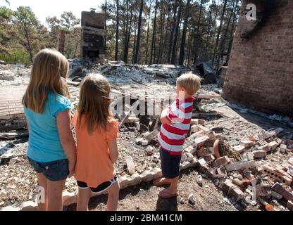 Bastrop County Texas USA, September 9, 2011: Somber children look at the remains of a home destroyed during massive wildfires that swept through their wooded neighborhood earlier in the month.  ©Marjorie Kamys Cotera/Daemmrich Photography Stock Photo