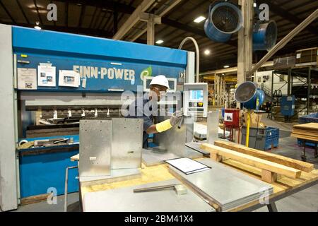 Houston Texas USA, October 20 2011: African-American male factory worker uses a computer-controlled crimping machine at a steel processing and manufacturing plant. ©Marjorie Kamys Cotera/Daemmrich Photography Stock Photo