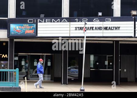 A person with a face mask walks past a movie theater marquee with the message 'Stay Safe and Healthy' in New York during coronavirus. 29th April 2020 Stock Photo