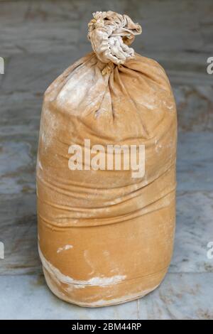 Flour in large burlap sack, Sack with wheat flour, lying on floor. Stock Photo